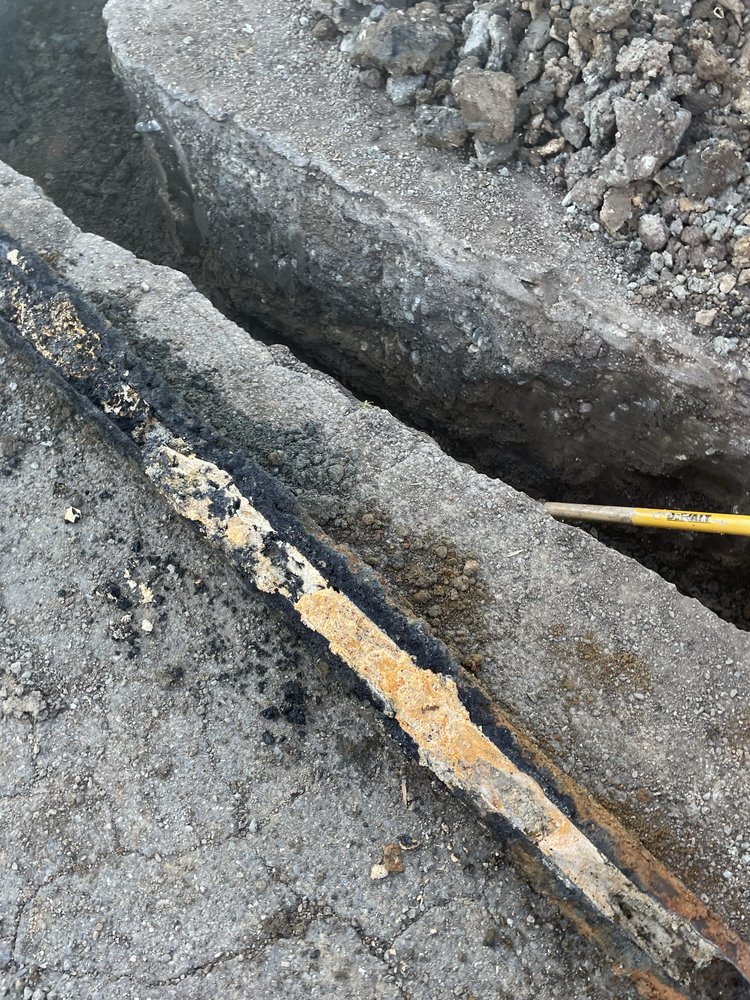 Excavated sewer line repair showing corroded cast iron pipe replacement
